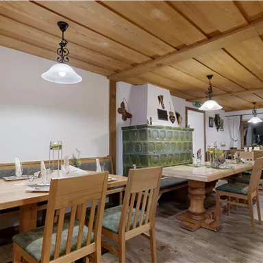 A cozy restaurant with wooden furniture and warm lighting. Tables are set for guests to create an inviting atmosphere.