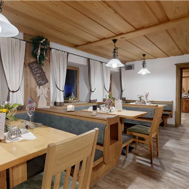 A cozy restaurant with wood interiors and light wooden tables. The atmosphere is inviting and rustic, with beautiful decorations and plants.