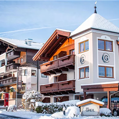 Ein schönes Hotelgebäude im Winter mit Schnee auf dem Boden und klarer Blauen Himmel. Die Architektur kombiniert traditionelle und moderne Elemente.