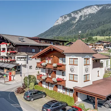 Ein malerisches Hotelgebäude inmitten einer schönen Berglandschaft. Die Umgebung ist grün und einladend, ideal für einen entspannenden Aufenthalt.