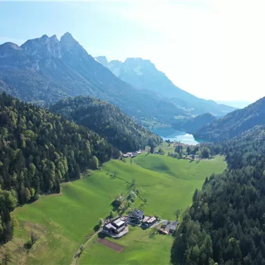 Eine malerische Landschaft mit grünen Wiesen, Bergen und einem klaren See. Die natürliche Schönheit der Umgebung strahlt Ruhe und Frieden aus.