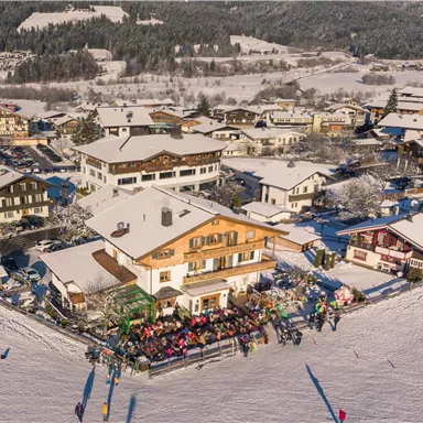 Ein malerisches Dorf im Winter mit schneebedeckten Dächern. Menschen genießen die frische Luft und die winterliche Landschaft.