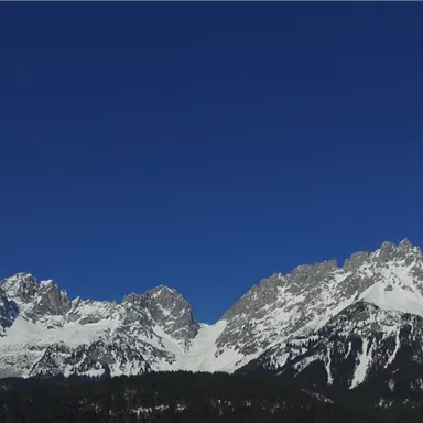 An impressive mountain landscape with snow-covered peaks and a clear blue sky. The natural beauty of the mountains radiates tranquility and grandeur.