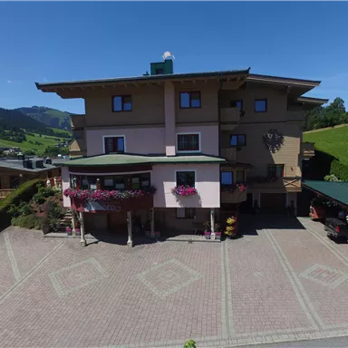 A charming building in a picturesque landscape. The facade is adorned with flowers and there is a spacious parking lot.