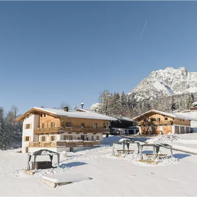 A picturesque landscape with snow-covered huts and high mountain peaks. The clear sky gives the winter idyll a special atmosphere.