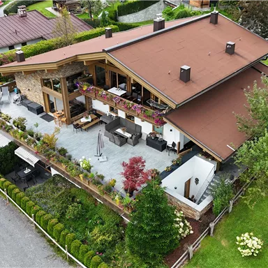 Ein schönes Haus mit einem großen Garten und einer Terrasse. Die Umgebung ist grün und gepflegt.