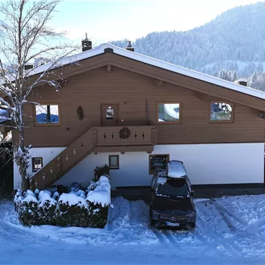 Ein gemütliches Holzhaus im Schnee mit einer schönen umliegenden Landschaft. Die Temperaturen sind kalt, und die Umgebung ist mit einer dicken Schneeschicht bedeckt.