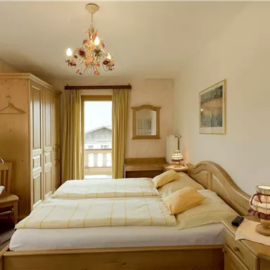 Ein gemütliches Schlafzimmer mit zwei Einzelbetten und hellen, warmen Farben. Der Raum verfügt über einen Balkon und ein Holzmobiliar.