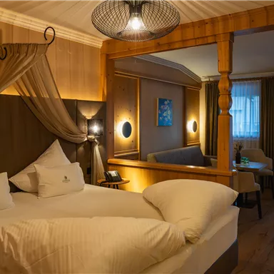 Ein gemütliches Hotelzimmer mit einem großen Bett und elegantem Dekor. Die warmen Farben und die schöne Beleuchtung schaffen eine einladende Atmosphäre.