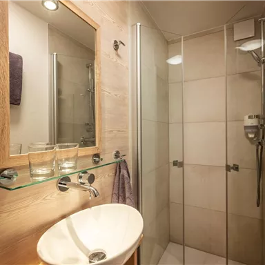 Ein modernes Badezimmer mit Dusche und Waschbecken. Der Raum ist hell und minimalistisch gestaltet.