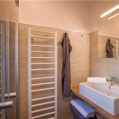 Ein modernes Badezimmer mit einer klaren Dusche und einem stilvollen Waschbecken. Die Wände sind hell und die Einrichtung ist minimalistisch.