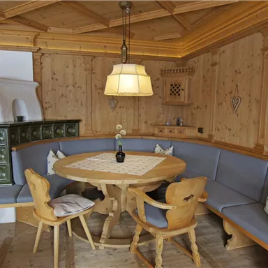 Ein gemütlicher Essbereich aus Holz mit einem runden Tisch und einer Sitzbank. Sanfte Beleuchtung schafft eine einladende Atmosphäre.