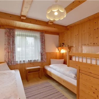 Ein gemütliches Zimmer mit Holzvertäfelung und zwei Betten. Das lichtdurchflutete Zimmer hat ein freundliches Ambiente.