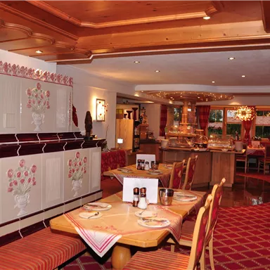 A cozy restaurant with wooden furniture and an inviting atmosphere. The tables are set and the walls are beautifully decorated.