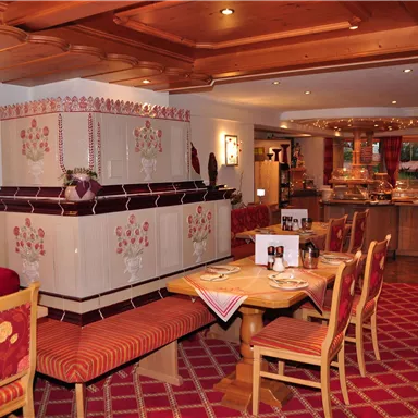 A cozy restaurant with wooden tables and traditional furniture. In the background, a buffet area can be seen.