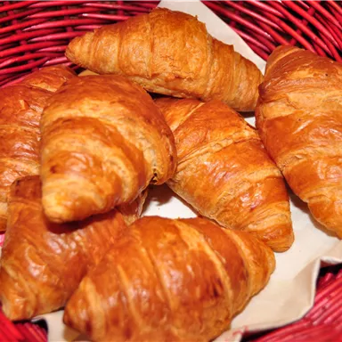 A basket of fresh, golden-brown croissants. They look delicious and crispy.