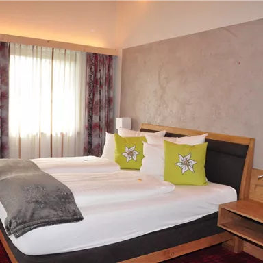 A modern hotel room with two beds and a cozy atmosphere. The windows let in plenty of natural light and the decor is simple and appealing.