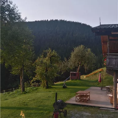 A beautiful garden with a wooden cabin and a mountain landscape in the background. A hot air balloon floats in the sky.