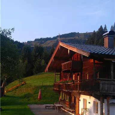 A charming wooden house in a picturesque landscape. A hot air balloon hovers above the house in a clear sky.