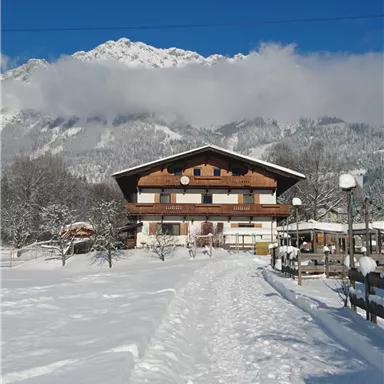 A beautiful building in the snow with mountains in the background. The clear blue sky complements the wintry landscape.