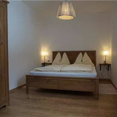 A cozy bedroom with a double bed and two nightstands. The room features warm wooden details and soft lighting.