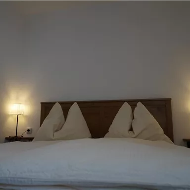 A cozy bedroom with a large bed and two nightstands. The pillows are in a nice shape, and soft light from the lamps creates a pleasant atmosphere.