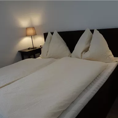 A cozy bedroom with a double bed and two pillows. Next to the bed are nightstands with lamps.