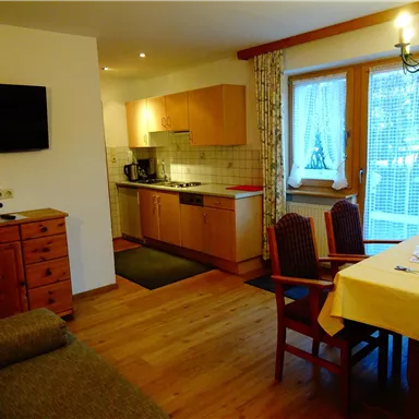 A cozy kitchen with a dining area and a living room. The decor is modern and inviting.