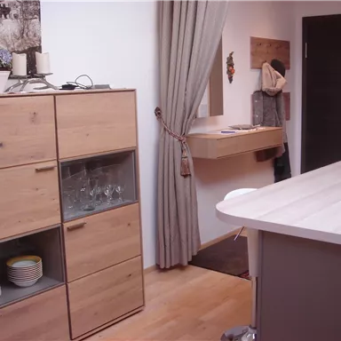 Eine moderne Küche mit Holzmöbeln und einem offenen Raumgefühl. Der Raum ist hell und einladend, mit einem Küchentresen und Stauraum.