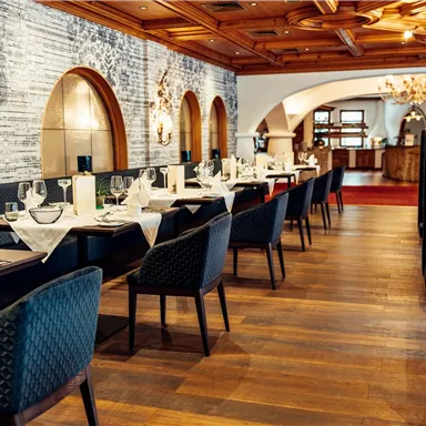 An elegant restaurant with set tables and chairs. The warm wood and light elements create an inviting atmosphere.