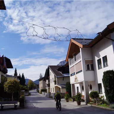 Eine ruhige Straße mit traditionellen Häusern und einem klaren Himmel. Auf einer der Straßen hängen dekorative Lichter.
