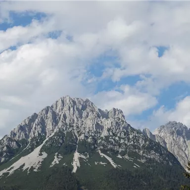 A stunning mountain with rugged cliffs and green slopes. The sky is partly cloudy, creating a majestic atmosphere.