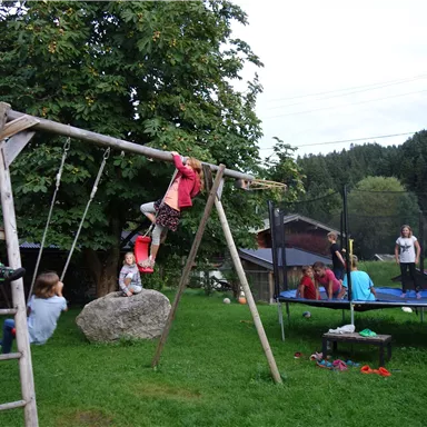 A playground with swings and a trampoline.
Children are playing and having fun in a green environment.