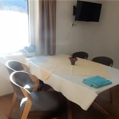 Ein gemütlicher Essbereich mit einem Tisch und Stühlen. Durch das Fenster fällt Licht in den Raum.