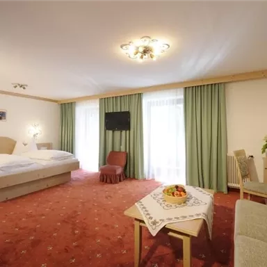 Ein gemütliches Hotelzimmer mit zwei Betten und einem schönen Ausblick. Der Raum ist hell und freundlich gestaltet, mit einem kleinen Tisch und einem Sofa.