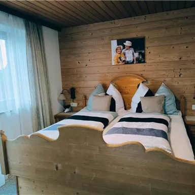 Ein gemütliches Schlafzimmer mit einem holzverkleideten Wänden und einem großen Bett. Neben dem Bett stehen Nachttische, und ein Bild hängt an der Wand.