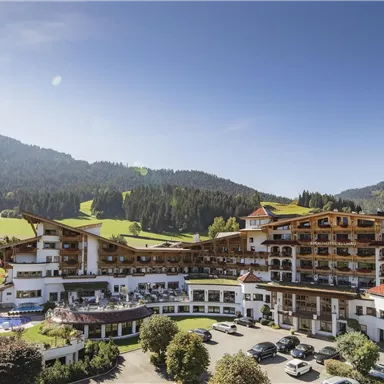 A modern hotel set in a picturesque mountain landscape. Surrounded by green meadows and trees, it offers an inviting atmosphere.