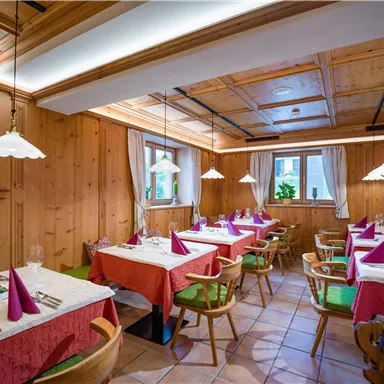 Ein gemütliches Restaurant mit Holzwänden und stilvollen Lampen. Die Tische sind liebevoll gedeckt und warten auf Gäste.