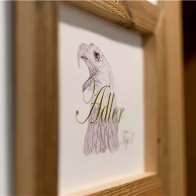 A piece of art featuring a drawn eagle's head and the inscription "Eagle". The image is framed in a wooden frame.