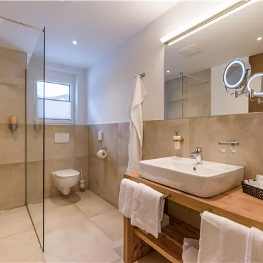 A modern bathroom with a glass shower and a rectangular sink. The walls are in neutral tones, and the decor is minimalistic.