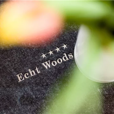 A blurry image with the inscription "Echt Woods" and four stars. In the background, parts of a flower can be seen.