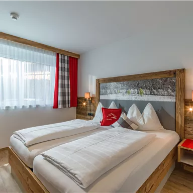 A cozy bedroom with two single beds and a stylish wood design. Large windows let in plenty of daylight and create a pleasant atmosphere.