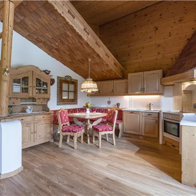 Eine gemütliche, moderne Küche mit Holzregalen und einem runden Esstisch. Der Raum hat eine warme Atmosphäre und ist gut ausgestattet.