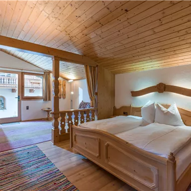 Ein gemütliches Zimmer mit Holzmöbeln und zwei Betten. Große Fenster bieten einen Blick auf den schönen Außenbereich.