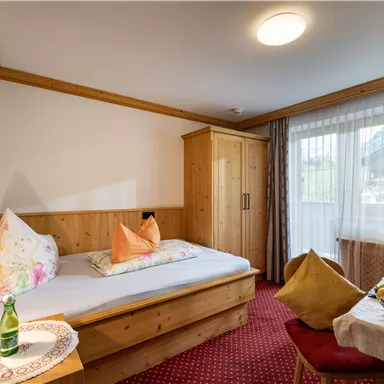 Ein gemütliches Hotelzimmer mit Holzverkleidung. Es ist mit einem Bett, einem Tisch und einem schönen Ausblick ausgestattet.