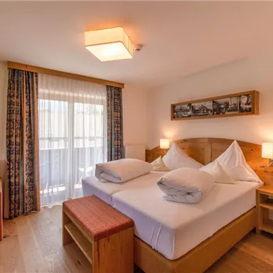 Ein modernes Schlafzimmer mit Holzdetails und einem Doppelbett. Das Zimmer verfügt über einen Balkon und eine gemütliche Sitzecke.