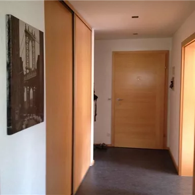 A corridor with wooden paneling and a gray wall. On the wall hangs a picture of a bridge.