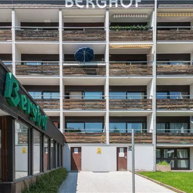 A modern building named "Berghof". The facade has several balconies and is surrounded by green spaces.