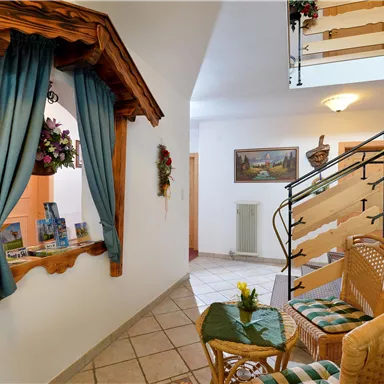 An inviting hallway with wood decor and blue curtains. A cozy seating area with two wicker chairs and a small table.
