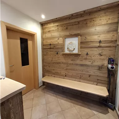 Ein einladender Flur mit einer Holzvertäfelung und einem Sitzbereich. Die Wände sind hell und die Beleuchtung ist warm und freundlich.